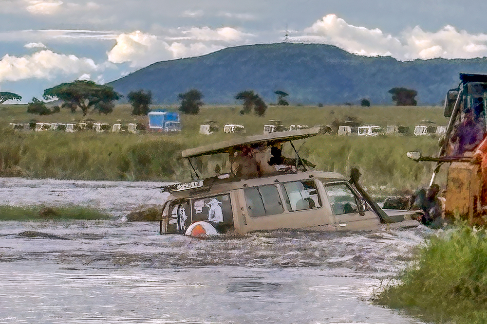 Vehicle stranded in an overflowing Tanzanian river being towed to safety by a Caterpillar machine