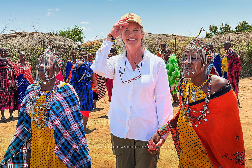 Author and travel writer Sheri Williams standing among Maasai women in Amboseli, Kenya.